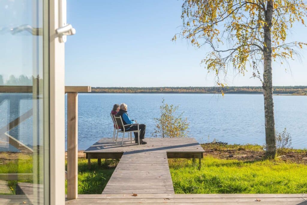 Par osm sitter på brygga utanför stuga och njuter av höst